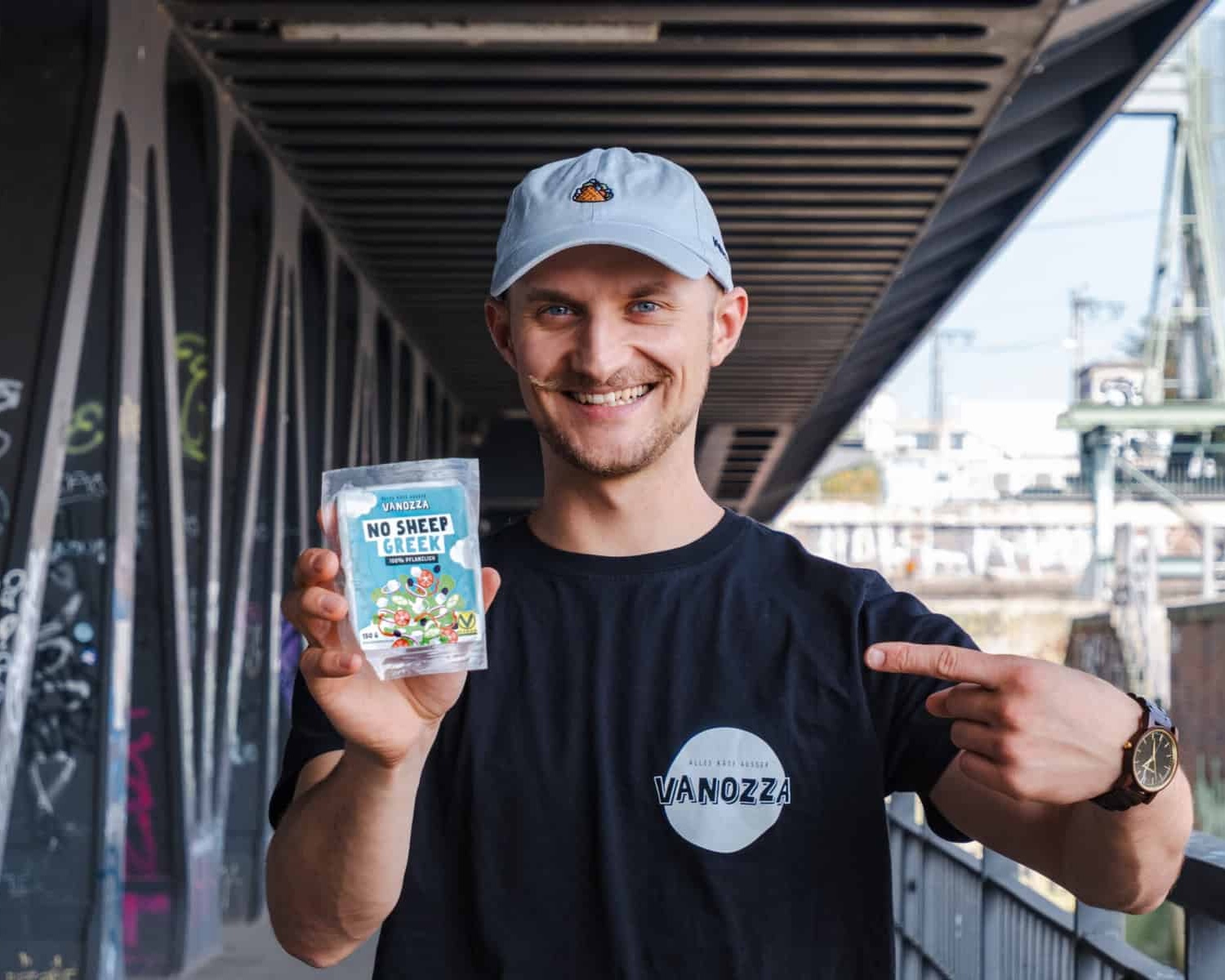 Nico Hansen, Gründer und Geschäftsführer der vanozza foods GmbH mit dem neuen Produkt "No Sheep Greek", einer pflanzlichen Alternative für Feta nach griechischer Art auf einer Brücke in Hamburg